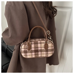 Model view of a brown plaid oval crossbody bag paired with a classic wool coat