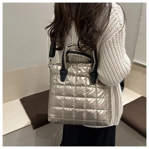Champagne gold quilted tote bag with metallic finish and black straps on a casual outfit