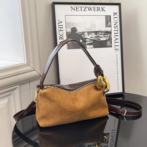 Vintage brown suede handbag with gold chain detail and leather strap on a glossy table