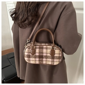 Detail view of retro plaid woolen handbag with round leather handles and metal hardware