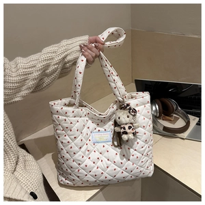 Detail of white quilted tote bag with red heart patterns and cute cat plush pendant