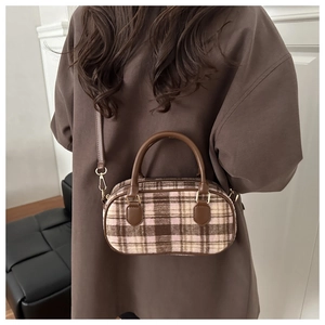 Detail of wool fabric checkered mini Boston bag with leather handles on a model