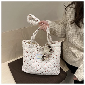 Close-up of white quilted tote bag featuring red hearts and a cute plush cat pendant