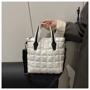 Detail of white quilted tote bag with black straps and square stitching pattern