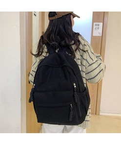 Detailansicht der schwarzen Cord-Textur und der geflochtenen Seilreißverschlüsse am Rucksack