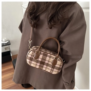 Detail of vintage brown plaid Boston bag with leather handles and gold-tone hardware