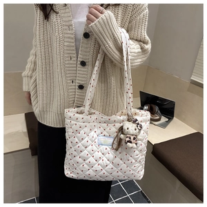 Detail of white quilted tote bag with red heart patterns and cute kitty plush charm