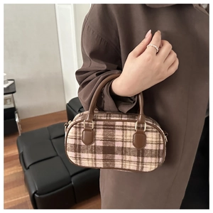 Detail of checkered tweed handbag in brown and pink with leather handles and gold buckles