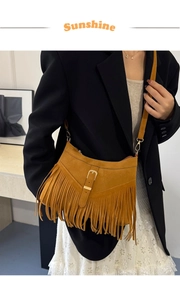 Detailed view of yellow fringe crossbody bag showing tassel decor and V-stitching