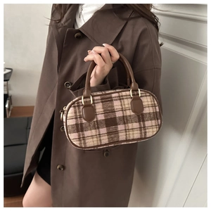 Detail of checkered oval handbag with brown leather handles and golden metal hardware