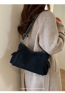 Detail van minimalistische zwarte matte leren crossbodytas met zijzakken op een model