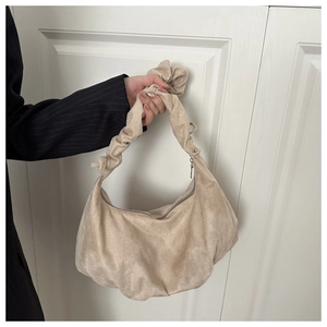 Détail du sac croissant en daim beige montrant la bandoulière froncée et la fermeture