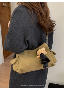Detail van olijfgroene crossbodytas met zijvakken en een schattige kattenhanger