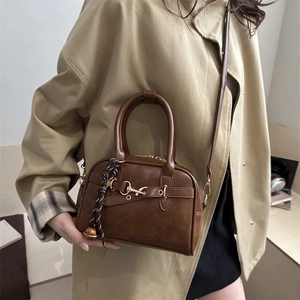 Brown vintage faux leather crossbody bag with decorative strap and bell on a model
