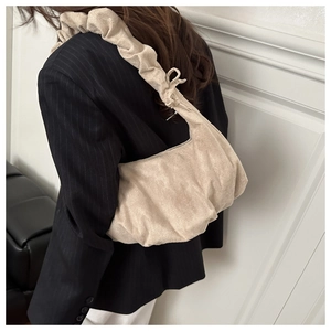 Sac à main beige plissé avec une bandoulière nouée élégante porté par un mannequin