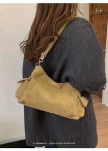Detail van mosterdgele retro crossbodytas met zilveren gesp op grijze wollen jas
