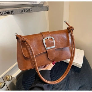 Détail du sac rétro marron caramel avec grande boucle argentée et nœuds sur la bandoulière