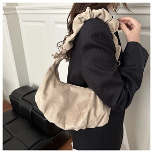 Détail du sac beige plissé avec bandoulière froncée porté par un mannequin