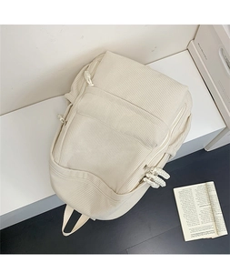 Detail eines cremefarbenen Cord-Rucksacks mit Taschen und Nylon-Reißverschlüssen