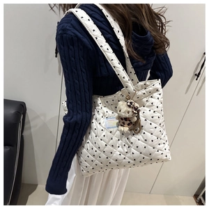 Detail of white quilted tote bag with heart patterns and a cute leopard print plush charm