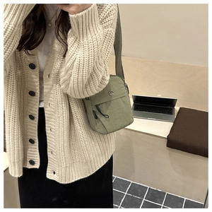 Detail of sage green nylon crossbody bag with metal M logo and adjustable strap