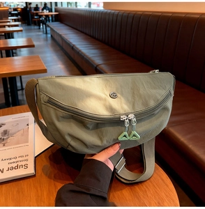Detailed close-up of olive green nylon crossbody bag with multi-zipper and silicone pulls