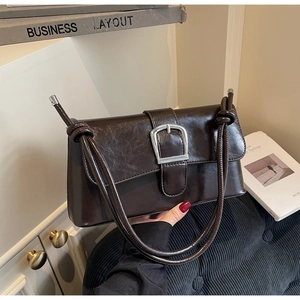 Détail du sac baguette marron foncé avec boucle carrée argentée et bandoulière nouée fine