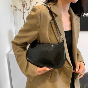 Minimalist black glossy crescent underarm bag with pleated texture and gold zipper
