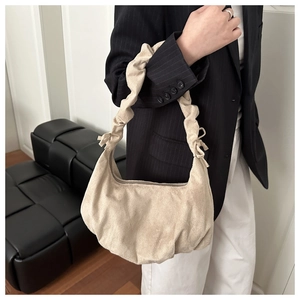 Gros plan du sac beige plissé en velours montrant la texture et la forme de croissant