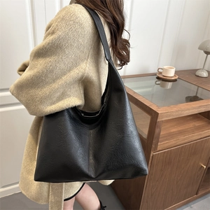 Grand sac fourre-tout noir mat avec large bandoulière porté par un mannequin en intérieur