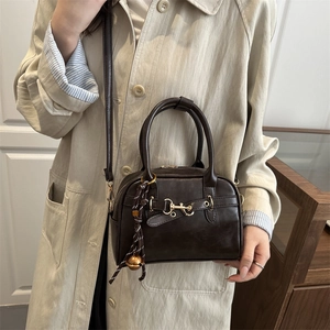 Retro dark brown crossbody bag with gold buckle and woven bell charm on model