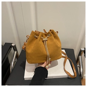 Detail of suede bucket bag with gold chain drawstring and elegant pearl accents