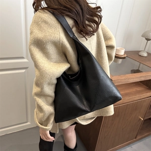 Grand sac cabas vintage en cuir noir porté par un mannequin dans un décor chaleureux