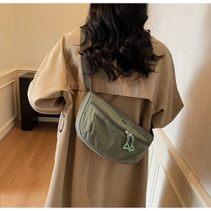 Détail du sac bandoulière en nylon vert olive avec tirettes de zip triangle néon
