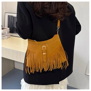 Detail of camel suede fringe crossbody bag with gold buckle on a model in black blazer