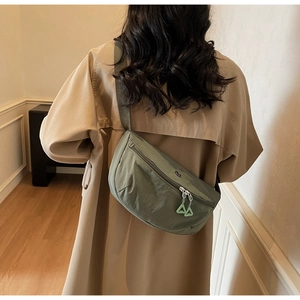 Rear view of a model wearing an army green nylon crossbody bag with triangle zipper tabs