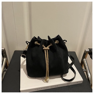 Detail of black drawstring bucket bag with gold chain and white pearl accents