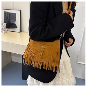 Detailed view of the ochre suede crossbody bag with long fringes on a model in a blazer