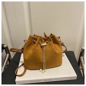 Detail of brown suede bucket bag with gold chain, pearl charm, and drawstring closure