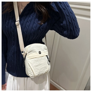 Detail of off-white crossbody bag with nylon texture, metal logo and adjustable strap