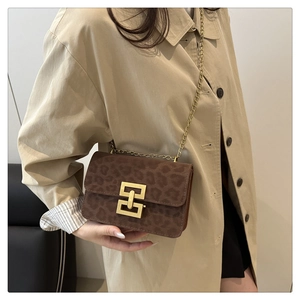 Detail of leopard print crossbody bag with gold geometric lock on beige trench coat