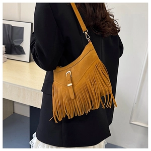 Rear view of a chic brown suede tassel tote bag worn over a black blazer for a stylish look