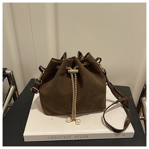 Detail of coffee suede bucket bag with gold chain drawstrings and pearl charm