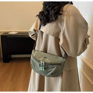 Detail of dark green nylon crescent bag with double zippers and lime green pull cords
