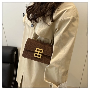 Detail of vintage leopard print crossbody bag with gold chain strap on beige trench coat