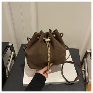Close-up of brown suede bucket bag featuring gold chain drawstring and pearl pendants