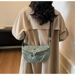 Detail of army green nylon crescent crossbody bag featuring adjustable strap and dual zippers