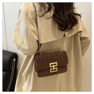 Leopard print crossbody bag detail with golden chain and lock on beige coat
