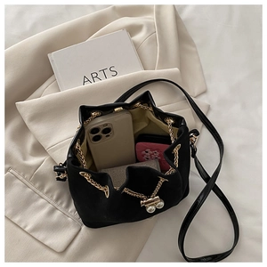 Detail view of black drawstring bucket bag interior with pearl charms and gold chain
