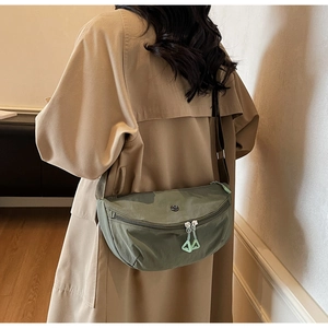 Detailed shot of an olive green nylon crescent bag on a model wearing a khaki trench coat